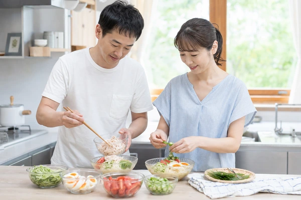 そうめんに卵や夏野菜を添える日本人男女