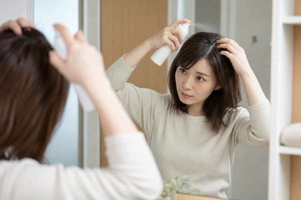 洗面所でドライシャンプーを使用する日本人女性