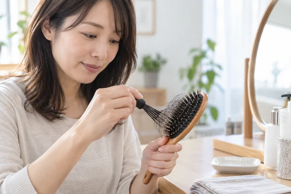 ヘアブラシから絡んだ髪を取り除く日本人女性