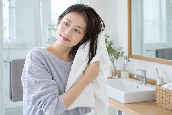 タオルで髪の水分をやさしく吸い取る日本人女性